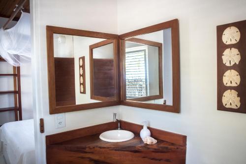 een badkamer met een wastafel en 2 spiegels bij Muita Paz Rooms in Atins