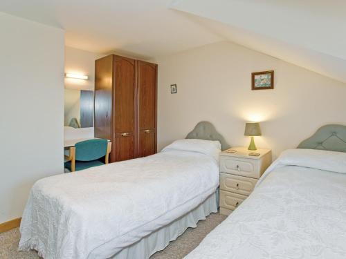 een slaapkamer met 2 bedden en een bureau bij Coot Cottage in Dilham