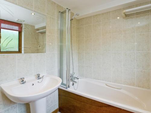 een badkamer met een wastafel en een bad bij Coot Cottage in Dilham