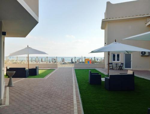 un patio con mesas y sombrillas y la playa en ALDIVA ROOMS en Torvaianica