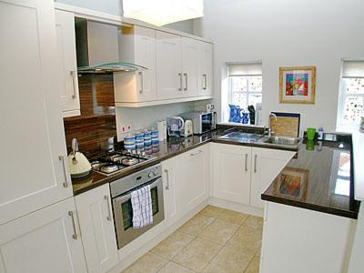 a kitchen with white cabinets and a stove top oven at The Dairy in Cromer