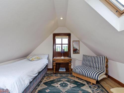 a attic bedroom with a bed and a chair at Coach House in Melton