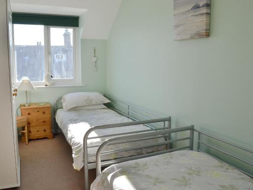 two twin beds in a room with a window at Aidan Cottage in Craster