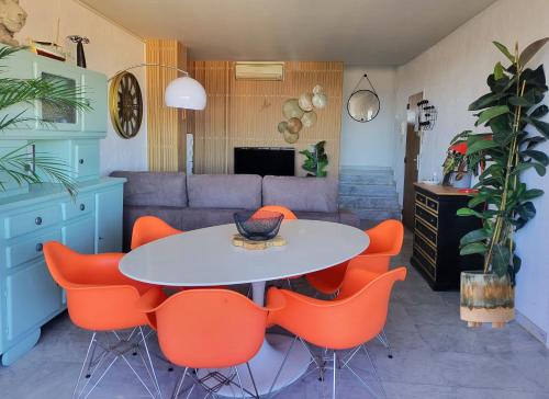 - un salon avec une table et des chaises orange dans l'établissement Bel appartement à 200m de la mer!, à Fréjus
