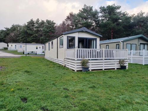 Casa móvil blanca con porche en un campo de césped en Foxglove 10 en Ringwood