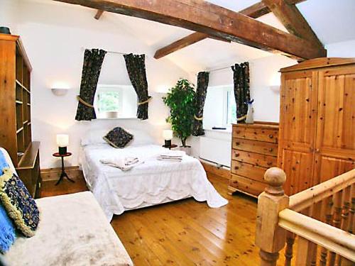 a bedroom with a bed in a room with wooden floors at The Barn in Waberthwaite