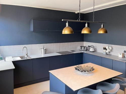 a kitchen with blue cabinets and a wooden table at The Cottage At Stanley Villa in Southport