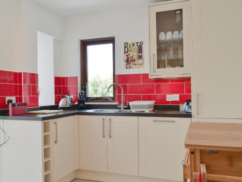 een keuken met witte kasten en rode tegels bij 3 Barf Cottages in Portinscale