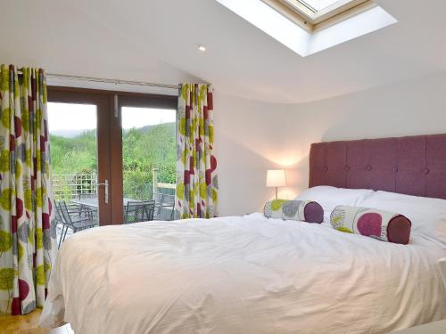 una camera da letto con un grande letto bianco e una finestra di 3 Barf Cottages a Portinscale