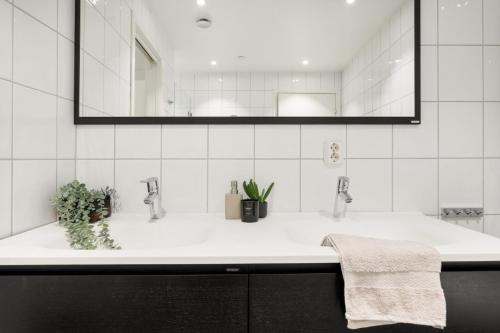 a white bathroom with a sink and a mirror at Fløyen Lux Apartment in Bergen