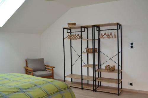 a room with a bed and a chair and shelves at L'Escale des remparts in Rocroi