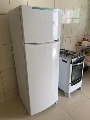 um frigorífico branco numa cozinha ao lado de um fogão em Apuama Hostel em Ubajara