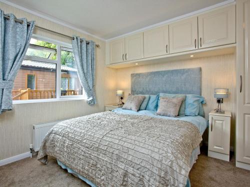 Forest Glade Lodge في Lanlivery: غرفة نوم بسرير كبير ونافذة
