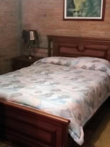 1 cama en un dormitorio con marco de madera en La Casa de los Patos, en Quito