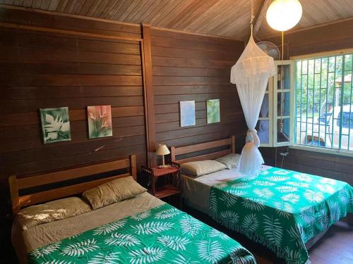 twee bedden in een kamer met houten wanden bij Casa Tapirapé - Barra Grande/BA in Barra Grande