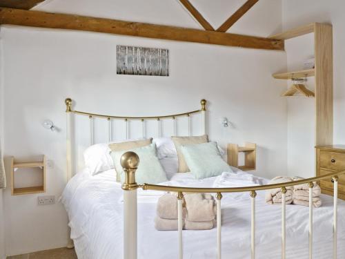 a bedroom with a bed with white sheets and pillows at The Cow Shed in Arlingham