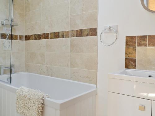 a white bathroom with a tub and a sink at The Cow Shed in Arlingham