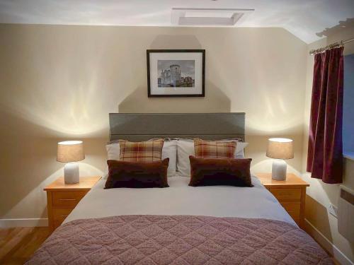 a bedroom with a large bed with two lamps at Pleacairn Cottage in Dalton