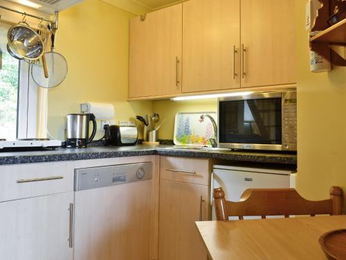 a kitchen with wooden cabinets and a microwave at Waterside Lodge in Port Appin