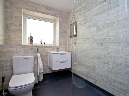 a bathroom with a toilet and a sink and a window at Orestone Garden Apartment in Dawlish