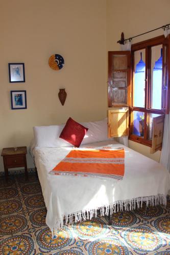 a bedroom with a bed with a red blanket on it at Hotel Gernika in Chefchaouene