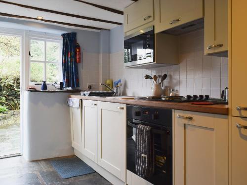 a kitchen with white cabinets and a black oven at Lobstone Cottage in Rosthwaite