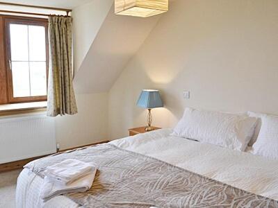 a bedroom with a large white bed with a window at Tara Cottage in Gordon