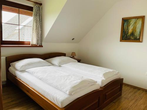 a bedroom with a bed with white sheets and a window at Penzion Pod Dratnikem in Svratka