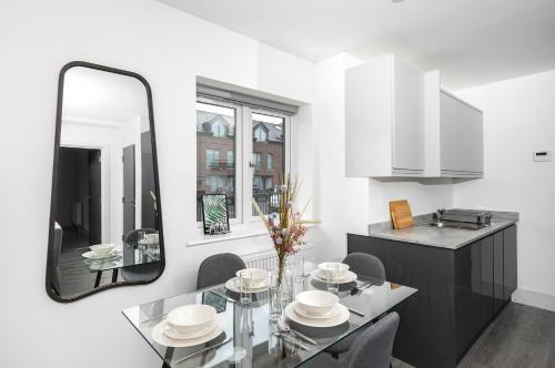 uma sala de jantar com uma mesa de vidro e um espelho em Skyvillion - London Enfield Chase Apartments with Parking & Wifi em Enfield