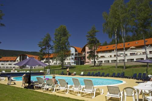 eine Gruppe von Personen, die an einem Pool auf Stühlen sitzen in der Unterkunft Lipno Lake Resort in Lipno nad Vltavou