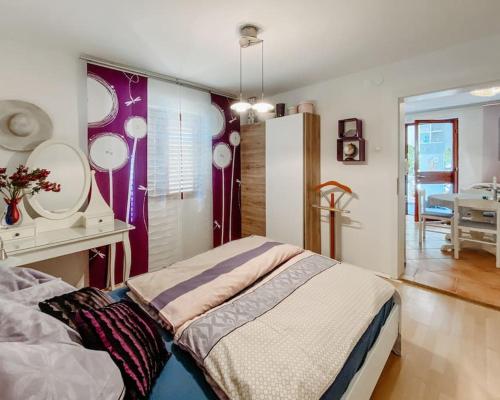 a bedroom with a bed and a table with a mirror at Apartment Nadica Sabunike in Privlaka