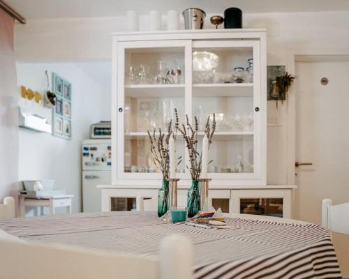 a dining room table with a white cabinet and vases on it at Apartment Nadica Sabunike in Privlaka