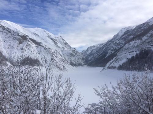 a view of a snowy mountain range with a lake at Hôtel Le Cassini in Le Freney-dʼOisans