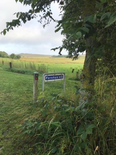a street sign next to a tree in a field at Porshus Ferielejlighed in Sundstrup