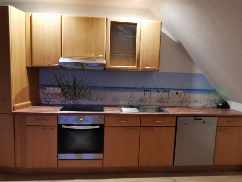 a kitchen with wooden cabinets and a stove top oven at Ostseeblick im Andersenhof in Kappeln