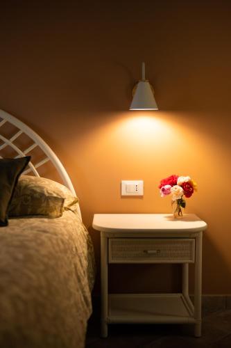 a bed with a table with a vase of flowers on it at L'ALBERO DELLA MANNA in Patti