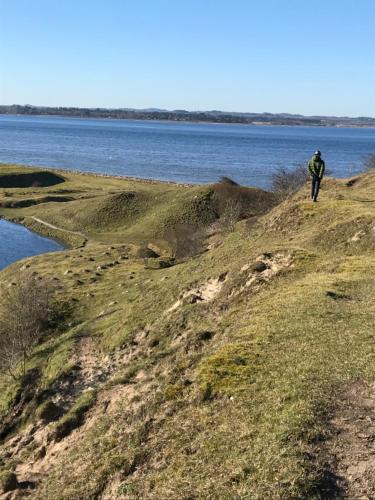 a man walking on a hill next to a body of water at Porshus Ferielejlighed in Sundstrup