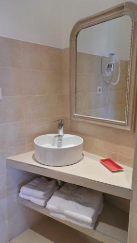 a bathroom with a sink and a mirror and towels at Hotel Relais Du Postillon in Antibes