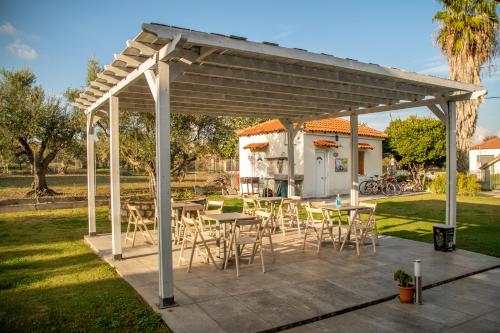 a wooden pergola with tables and chairs in a yard at Anastasios Olive Garden Apartments in Petalidi