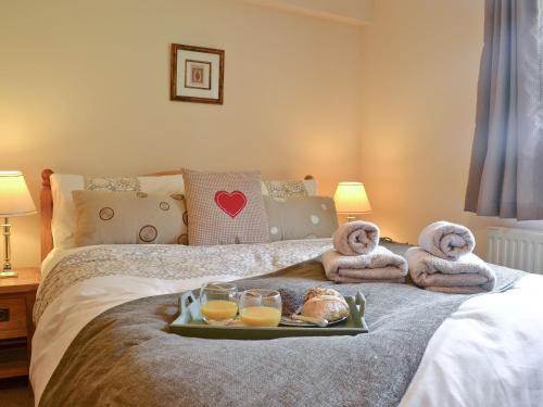 bandeja de comida en una cama con toallas y vasos de zumo de naranja en Ty Newydd Cottage en Hoel-galed