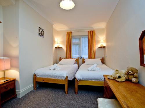 um quarto com duas camas e um urso de peluche no chão em 1 Roundham Heights em Paignton