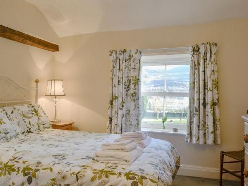 a bedroom with a bed with a window at Bridge House in Threlkeld