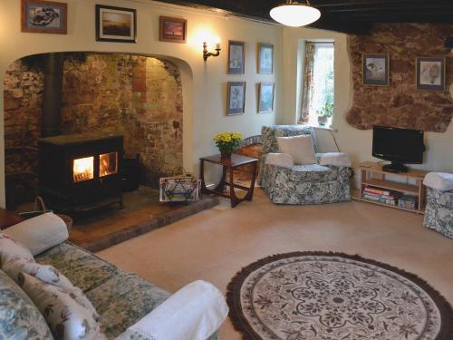 a living room with a fireplace and couches and a television at Old Rectory Cottage in Oake