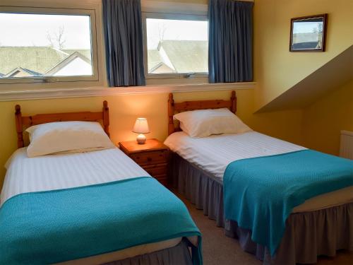 two beds in a room with two windows at Alexandra Cottage in Windermere