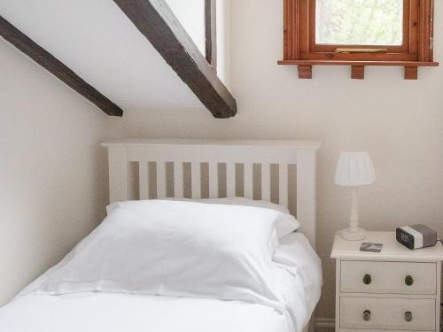 a bedroom with a white bed and a window at Lilac Cottage Dunstan in Craster