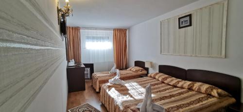 een hotelkamer met 2 bedden en een bank bij Hanul Izvorul Rece Sinaia in Sinaia