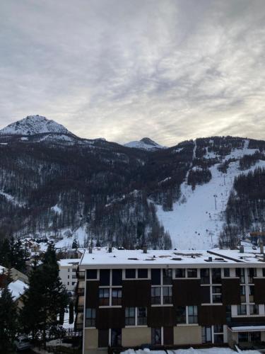un bâtiment avec une montagne enneigée en arrière-plan dans l'établissement Le Flocon - 6 personnes, à Saint-Chaffrey