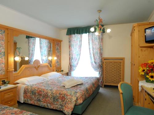 a bedroom with a bed and a window and a television at Hotel Barance in Alleghe