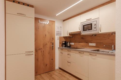 a kitchen with white cabinets and a microwave at Hotel Garni Schönblick in Sölden