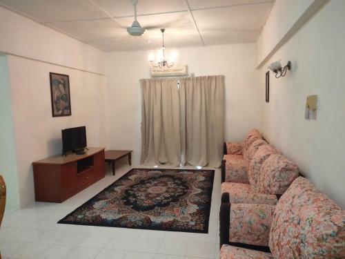 uma sala de estar com um sofá e uma televisão em Lumut Valley em Lumut